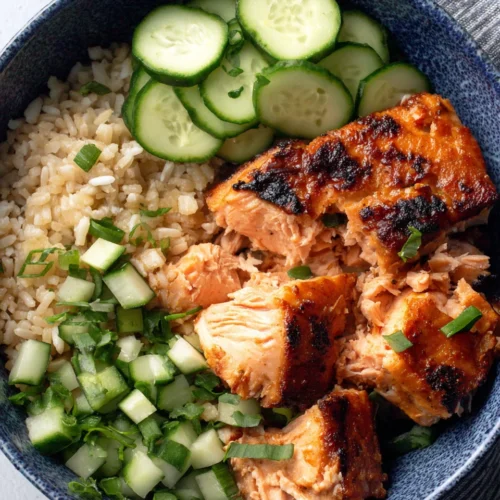 Delicious Air Fryer Salmon Recipe for All the Family 1 Crispy air fryer salmon served with rice and cucumbers.