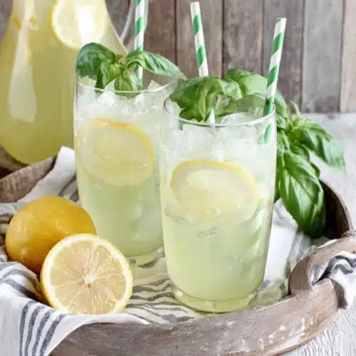 Basil Lemonade: Refreshingly Unique and Invigorating 1 Two glasses of basil lemonade with lemon slices and basil garnish on a tray