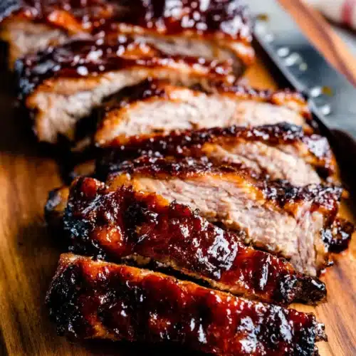 Sliced BBQ baby back ribs on a wooden board, glazed and tender