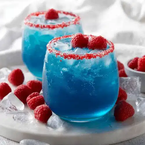 Blue Hawaiian Lemonade Punch: Refreshingly Fun and Easy 1 Two glasses of blue Hawaiian lemonade punch with raspberry garnish and ice