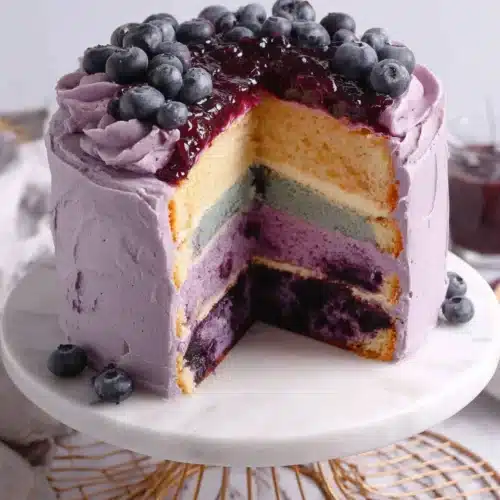 Blueberry Layer Cake: A Delightfully Sweet Treat 1 Blueberry layer cake with purple frosting and fresh blueberries, slice cut to show layers