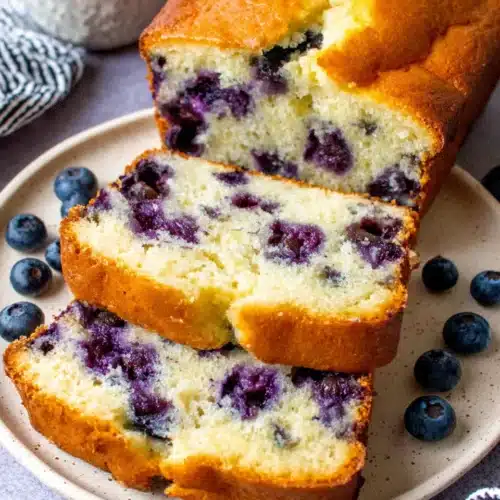 Delicious Blueberry Muffin Bread That Everyone Will Love 1 Sliced blueberry muffin bread on a plate with fresh blueberries