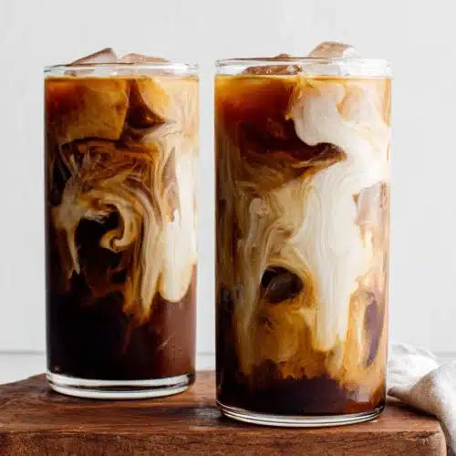 Cold Brew Coffee: Refreshing and Easy to Make! 1 Two glasses of cold brew coffee with milk swirls and ice, served on a wooden board