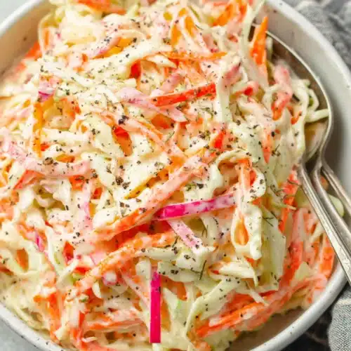 Cole Slaw Salad: A Refreshingly Crunchy Delight 1 Creamy cole slaw salad with cabbage, carrots, and apple in a white bowl