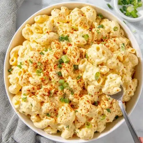 Deviled Egg Macaroni Salad: A Delightfully Creamy Treat 1 Creamy deviled egg macaroni salad in a white bowl with green onions and paprika