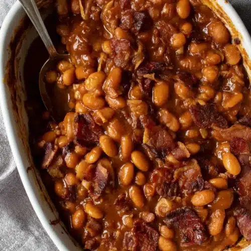 Healthy Baked Beans Recipe: A Delicious and Easy Delight 1 Healthy baked beans with bacon in a white dish, spoon serving, rich sauce