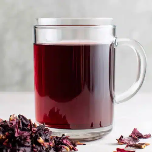 Hibiscus Tea: Refreshingly Tangy and Easy to Make 1 A glass mug of hibiscus tea with dried petals nearby