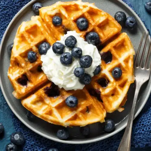 Low Calorie Blueberry Waffles: Deliciously Easy and Guilt-Free 1 Low calorie blueberry waffles topped with cream and fresh blueberries on a gray plate