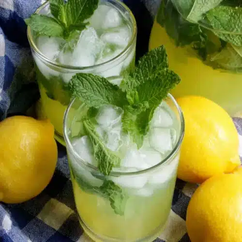 Moroccan Mint Lemonade: Refreshing and Zesty Delight 1 Moroccan mint lemonade with fresh lemons and mint on a checkered cloth