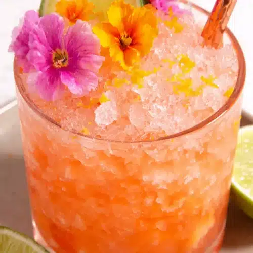 Pineapple Mango Rum Punch: A Refreshing Delight 1 Pineapple mango rum punch in a glass with ice, lime, and edible flowers