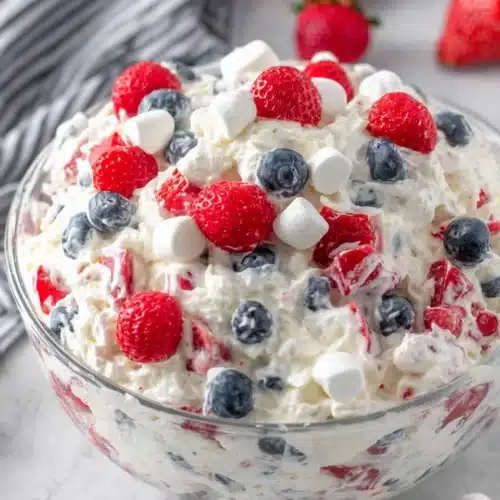 Delicious and Easy Red White and Blue Cheesecake Salad 1 Red white and blue cheesecake salad with fresh berries and marshmallows in a glass bowl
