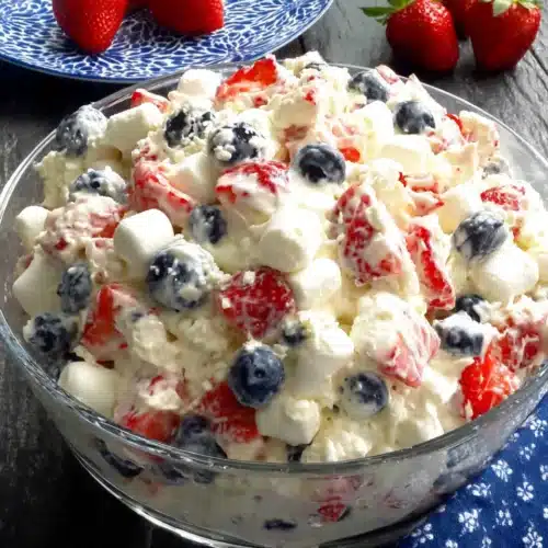 Red, White & Blue Cheesecake Salad: A Delightful Dessert 1 Red, white & blue cheesecake salad with strawberries, blueberries, and marshmallows in a glass dish