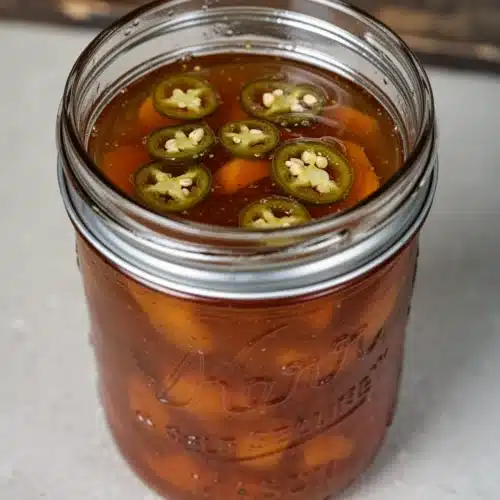 Apricot Jalapeno Jam: A Sweet and Spicy Delight 2 Apricot jalapeno jam in glass jars with silver lids, showcasing rich orange color and chunky texture