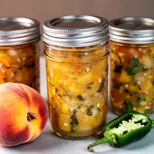 Homemade Peach Salsa: A Sweet and Spicy Delight 2 Homemade peach salsa in jars with fresh peaches and jalapeños