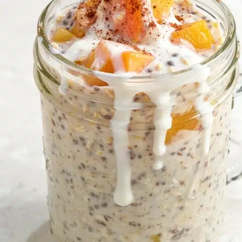 Delicious Overnight Peach Cobbler Oatmeal for Easy Mornings 2 Overnight peach cobbler oatmeal in a jar with peaches and cinnamon