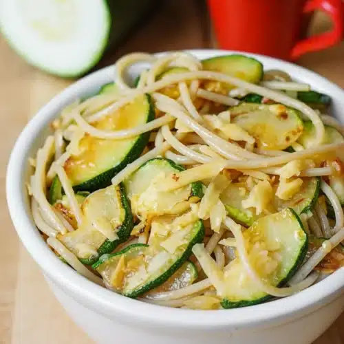 Easy Parmesan Zucchini Garlic Pasta: A Delightful Weeknight Dinner 2 Parmesan zucchini garlic pasta in a white bowl with fresh zucchini and red mug