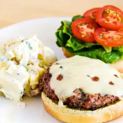 Turkey Burgers Recipe: Juicy and Delicious 1 Juicy turkey burger with melted cheese, lettuce, tomato, and potato salad on a plate
