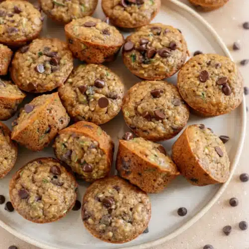 Delicious Whole Wheat Banana Zucchini Chocolate Chip Muffins 2 Whole wheat banana zucchini chocolate chip muffins on a plate with chocolate chips scattered around
