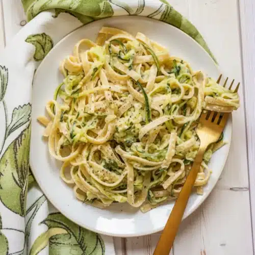 Zucchini Alfredo Pasta: A Creamy Delight for Weeknight Dinners 2 Creamy zucchini alfredo pasta with fettuccine and fresh zucchini ribbons on a white plate