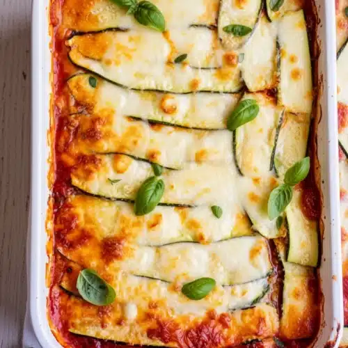 The Best Zucchini Lasagna Recipe You’ll Love 2 Zucchini lasagna with melted cheese and fresh basil in a white dish