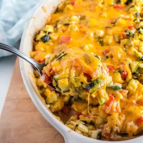 Zucchini Tomato Casserole with Rice: A Flavorful Delight 2 Zucchini tomato casserole with rice in a white dish, topped with melted cheese, being served with a spoon