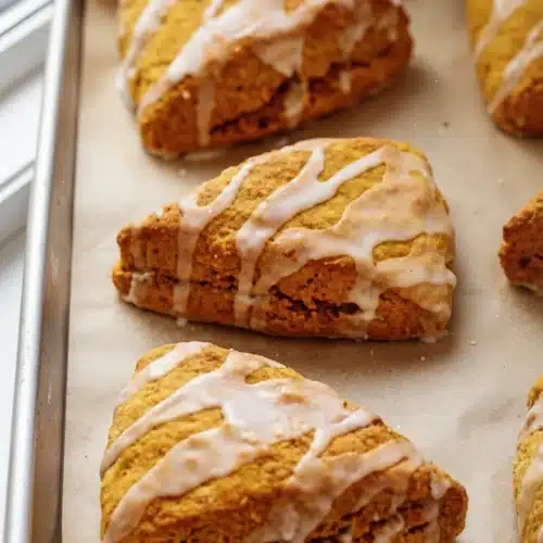 Harvest Pumpkin Scones: Deliciously Easy Treats 1 Golden harvest pumpkin scones with white glaze on a baking sheet